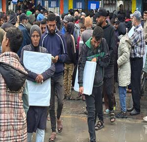 مواطنون يتجمعون في طابور للحصول على الشوادر من مركز توزيع تابع للأونروا في دير البلح في وسط قطاع غزة
